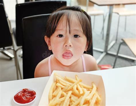 Child Girl Eating French Fries At Fast Food Restaurant Stock Photo
