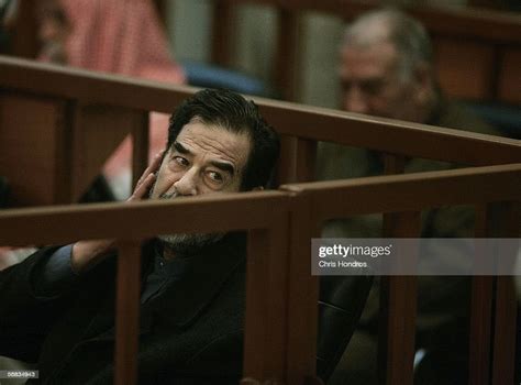 Former Iraqi Leader Saddam Hussein Looks Over From His Seat Toward