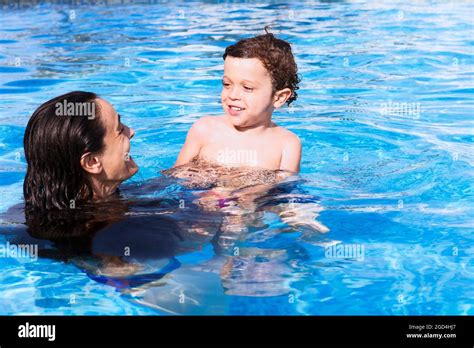 Mother And Son Bathing In The Poolboth Of Them Smiling Happily Looking At Each Other While