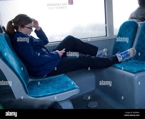 Teenager Mädchen In Schuluniform In Einem Bus Mit Füßen Auf Gegenüberliegenden Sitz
