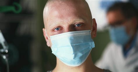 Bald Male Patient With Cancer Wearing Medical Mask And Looking At