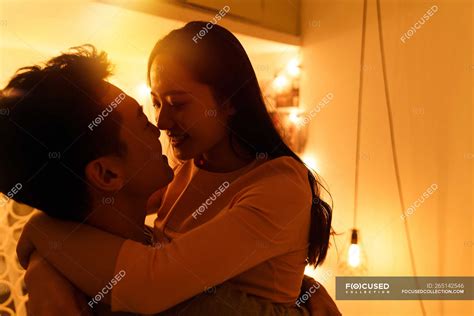 lado vista de feliz joven asiático pareja abrazos y besos en la noche — novia hombre stock