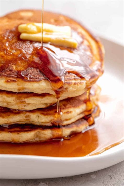 A Stack Of Fluffy Pancakes On A White Plate Served With Butter And