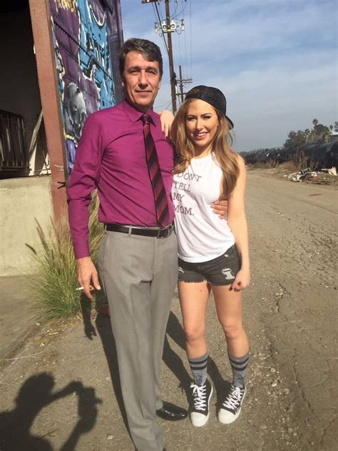 a man standing next to a woman in front of a graffiti covered wall and telephone pole