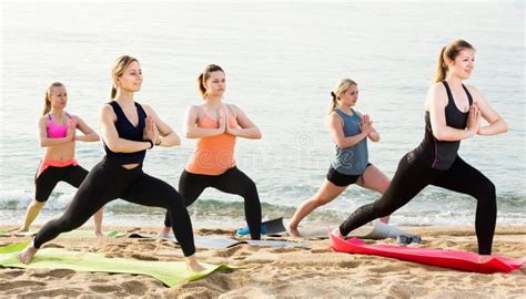 Group Of Sporty Girls Practicing Various Yoga Positions During Training On Beach Stock Image