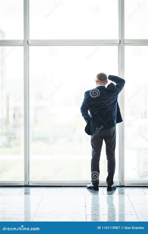 Portrait Of Smiling Senior Businessman Standing Looking Out Of Office