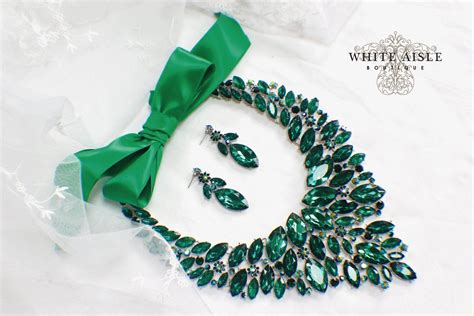 A Green Necklace And Earring Set On A White Background With The Words