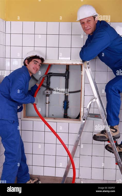 Plumbers Working In A Tiled Room Stock Photo Alamy