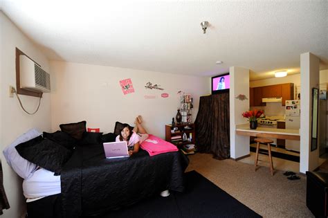 a woman laying on top of a black bed in a bedroom next to a tv