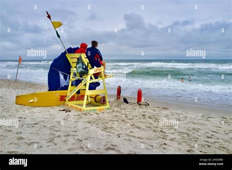 Two Lifeguards Sit In High Wooden Beach Chair Watching Swimmers On The