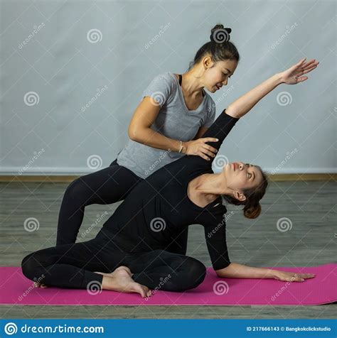 Asian Yoga Master Or Teacher Training And Supporting Newcomer Babe By Holding Her Arms To