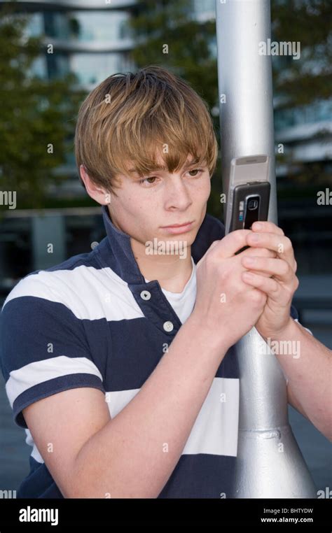 Teenage Boy Looking At Has Mobile Phone Reading Messages Or Looking At