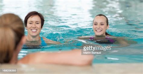 Portrait Of Smiling Women Leaning On Edge Of Swimming Pool High Res