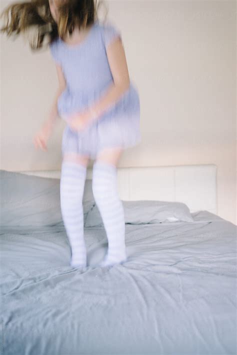 blurred image of girl jumping on the bed in purple stripey socks by stocksy contributor