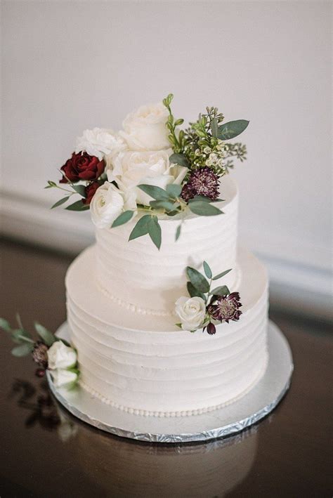A White Wedding Cake With Flowers And Greenery