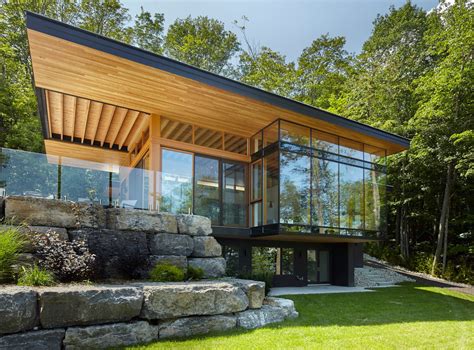 A Modern House In The Woods Surrounded By Rocks And Grass With Large