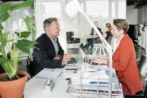 Happy Business People Having Discussion At Desk Stock Photo Dissolve