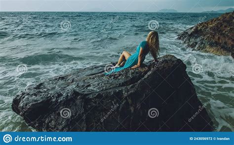 Woman Meditates Relaxes On A Rock Reef Hill In Stormy Morning Rain