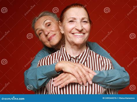 Two Pretty Older Women Hugging On Red Background Lifestyle Concept