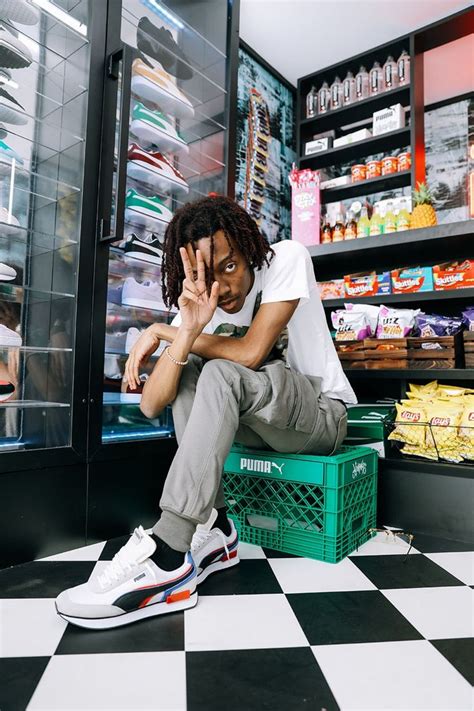 A Man Sitting On Top Of A Green Crate In Front Of A Store Filled With Food