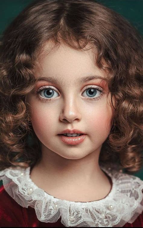 A Close Up Of A Doll With Curly Hair And Blue Eyes Wearing A Red Dress