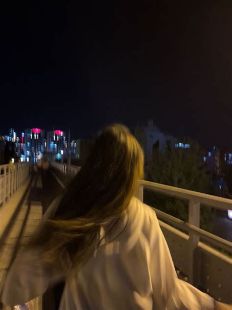 A Woman Walking Down A Bridge At Night With Her Long Hair Blowing In