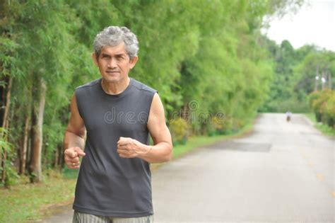 An Old Man Running Along The Road Among The Nature Atmosphere Stock