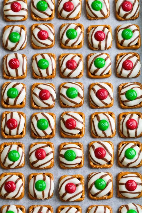 Hershey kiss blossoms with peppermint. Pretzel M&M Hugs in rows on parchment paper lined baking ...