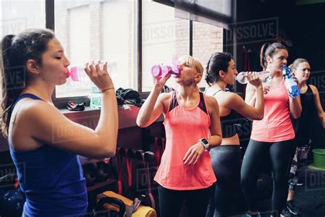 Group Of Women Training In Gym Taking A Break Drinking Bottled Water Stock Photo Dissolve