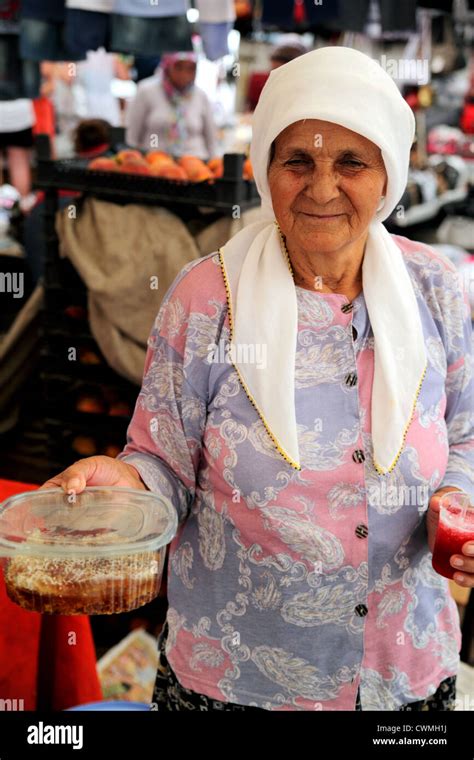 Upright View Of Elderly Turkish Woman Wearing Headscarf Holding Honeycomb For Sale In Market
