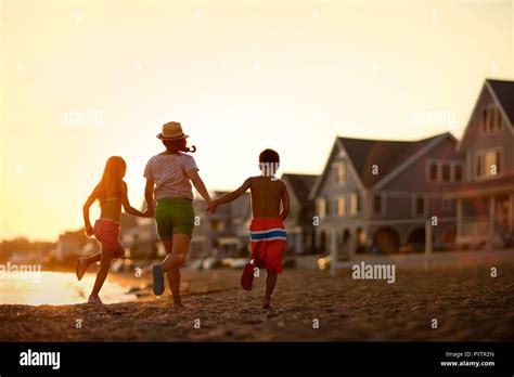 La Madre Y Sus Dos Hijos Tomados De La Mano Y Correr Por La Playa Al