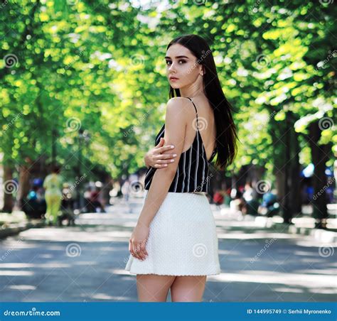 Young Girl Model Posing At The Park With Green Trees Looking Back Stock