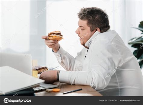 Hombre Negocios Con Sobrepeso Comiendo Hamburguesa Mientras Trabaja Oficina Fotografía De Stock