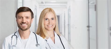 Female And Male Doctors Posing Standing In Hospital Hallway Indoors