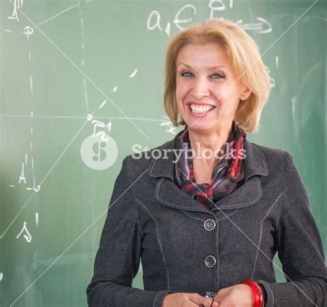 Smiling Teacher Standing In A Classroom Royalty Free Stock Image