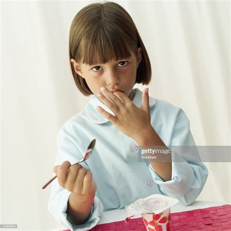 Portrait Of A Young Girl Licking Yoghurt Off Her Finger High Res Stock
