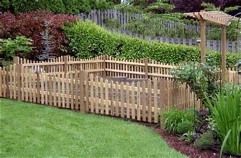 This fence surrounding a garden is stained with a diy solution made by soaking steel wool in vinegar and then using the slurry to add color to the wood. DIY Pallet Garden Fence | Pallets Designs
