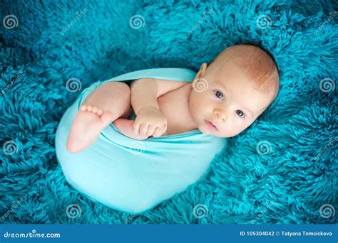 Cute Three Months Old Baby Boy In Blue Wrap Lying On A Blue Blanket
