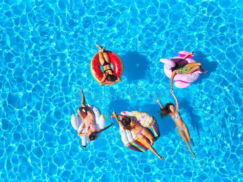 aerial of hot pretty girls in bikini swimming in pool on floaties top view from above