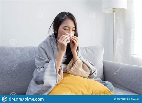 Sick Asian Woman Sitting Under The Blanket Whiles Sneezing With Tissue