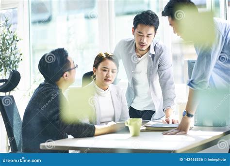 Group Of Four Asian Business People Working Together In Office Stock