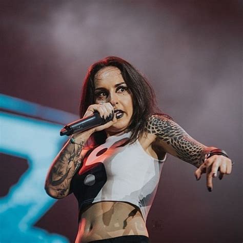 A Woman With Tattoos On Her Arm And Chest Holding A Microphone In Front