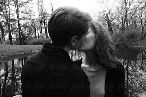 A Beautiful Couple Kissing Nearby Lake Del Colaborador De Stocksy