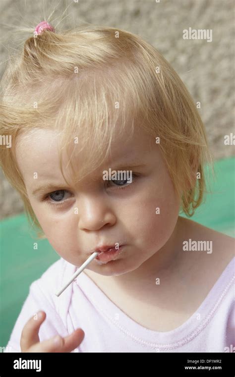 Headshot Of A 1 Year Old Girl Stanging Outside In The Sunshine Eating A