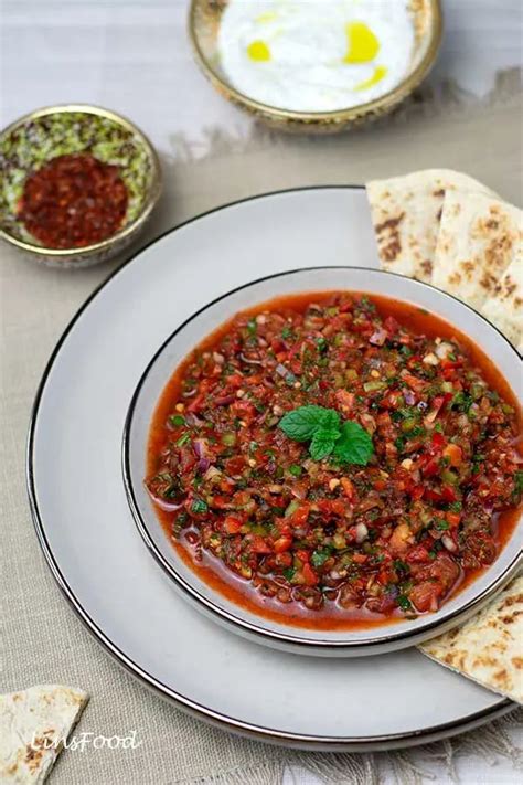 A White Plate Topped With A Bowl Of Chili And Pita Bread