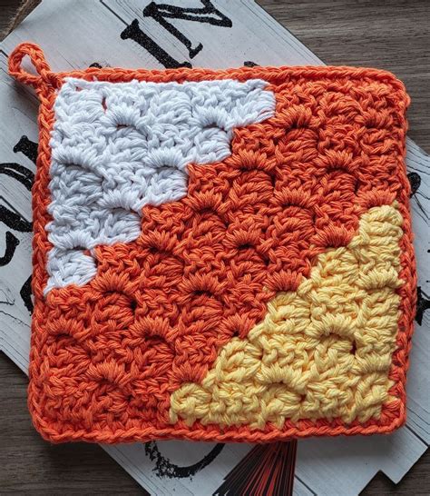 An Orange And White Crocheted Square On Top Of A Wooden Table