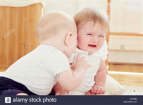 Crying Baby Girl With Baby Boy Leaning Toward Her Stock