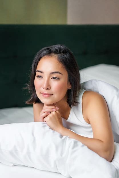 free photo vertical shot of beautiful asian woman lying in her bed on pillow covered in duvet