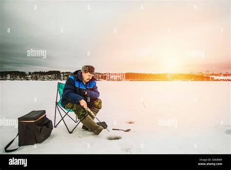 Man Ice Fishing In Frozen Lake Stock Photo Alamy