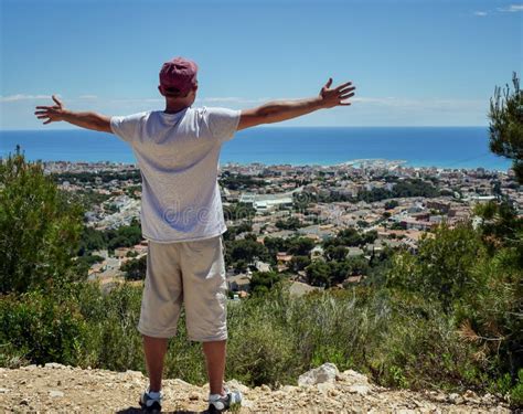 A Guy Stands On A Hilltop Spreading His Arms Wide To The Side Travel